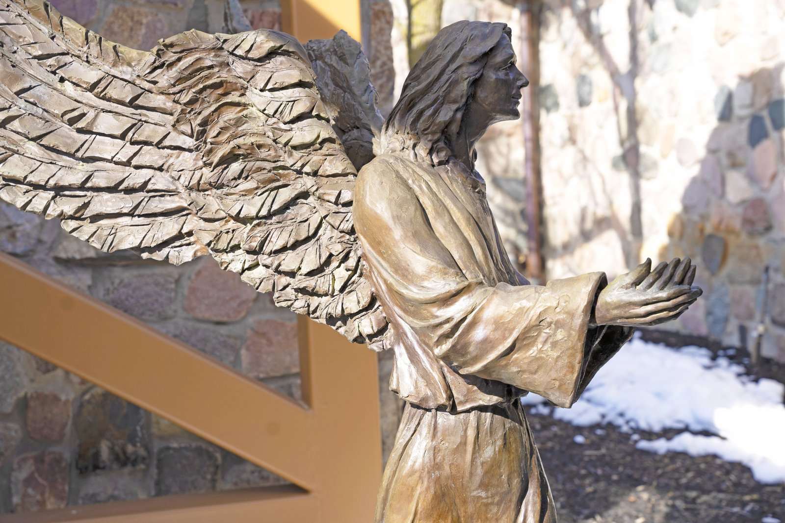 Uno de los dos ángeles mensajeros de bronce fundido de 5 pies de altura creados por Suzanne Young se encuentra frente al altar a través de una ventana en la parroquia St. Joseph the Worker en Lake Orion. Young creó a los ángeles durante la expansión de la iglesia en la década de 1990. (Gabriella Patti | Detroit Catholic)