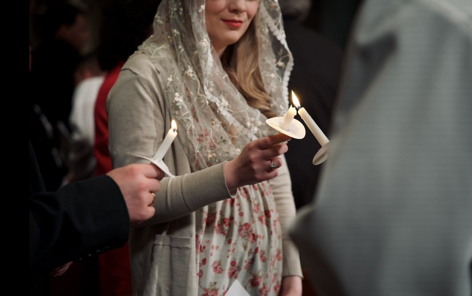 La luz de las velas se transmite de persona a persona mientras los asistentes comparten la luz de Cristo al comenzar la Vigilia Pascual.