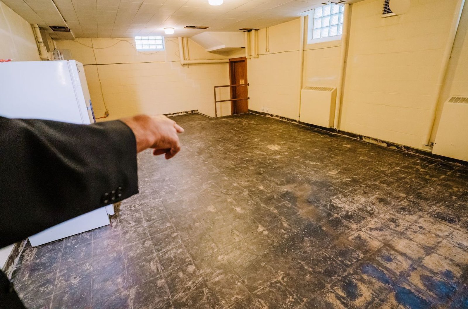 El padre Novelly señala baldosas dañadas en el sótano de la parroquia St. Matthew en el lado este de Detroit. El seguro cubre el costo de la reparación, pero el p. Novelly y otros párrocos locales dicen que se necesita una solución a largo plazo. (Valaurian Waller | Detroit Catholic)