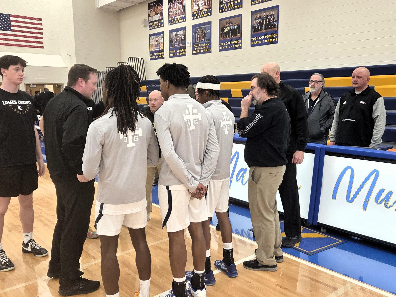 Mike Evoy (far right) overlooks a pre-game meeting between officials, coaches and captains of Detroit Loyola and Jackson Lumen Christi prior to tip-off of their playoff game.