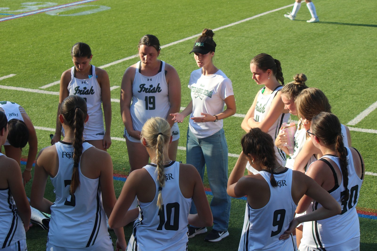 Ann Arbor Fr. Gabriel Richard coach Abigail Morton (in visor) reviews the flow of the game in a post-game talk with her players. The Fighting Irish, who have won the past three Catholic League Cardinal Division championships, were defeated 2-1 at Bloomfield Hills Cranbrook Kingswood on Sept. 2.