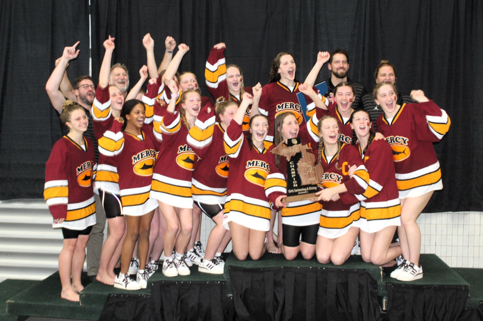 Mercy swimmers celebrate after receiving the MHSAA Division 2 state championship trophy Nov. 22 at Eastern Michigan University. It’s the Marlins’ fourth straight state title.